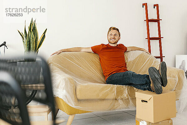 Smiling man sitting on sofa in living room at home