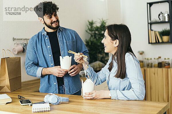 Lächelndes Paar isst Nudeln in der heimischen Küche