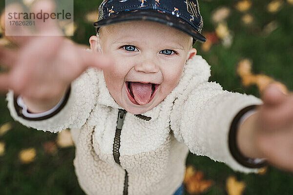 Fröhlicher Junge mit Mütze auf der Herbstwiese