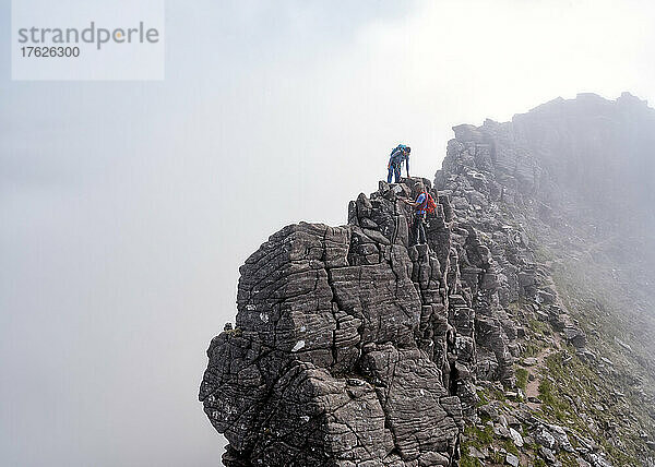 Mann hilft Frau beim Besteigen eines felsigen Berges