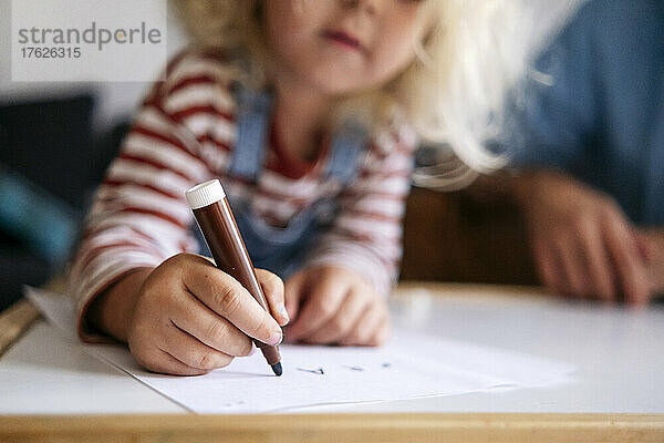 Junge zeichnet zu Hause mit Filzstift auf Papier