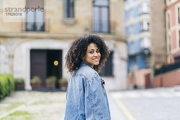Lächelnde Frau in Jeansjacke auf der Straße
