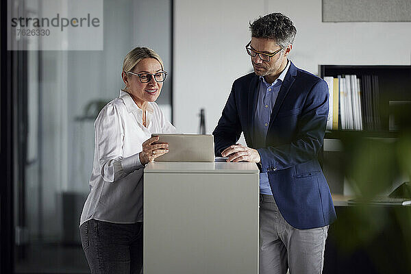 Geschäftskollege diskutiert über Tablet-PC am Schreibtisch im Büro