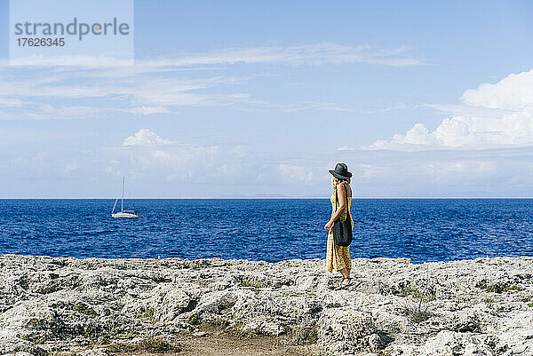 Tourist steht auf einem Felsen und blickt auf die Meereslandschaft  Menorca  Spanien