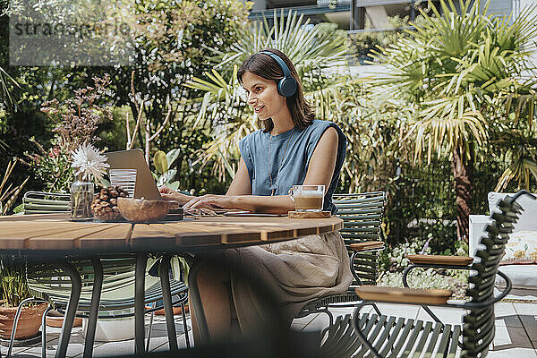 Geschäftsfrau tippt am Tisch im Garten auf dem Laptop