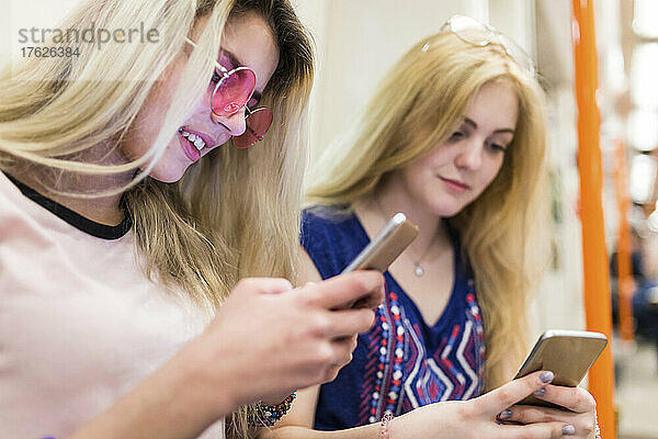 Blonde Teenager surfen mit Mobiltelefonen im Internet