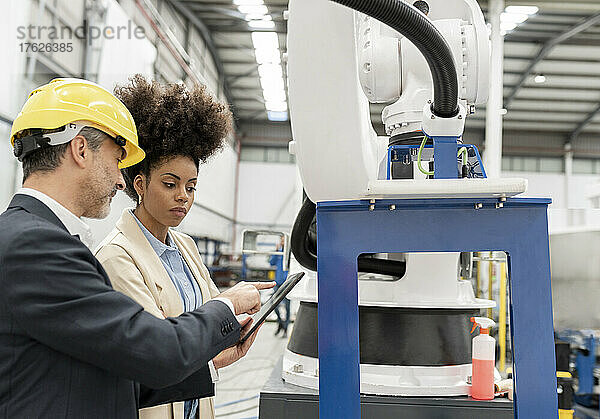 Ingenieur zeigt Entwickler Tablet-PC  der an Maschinen in der Fabrik steht