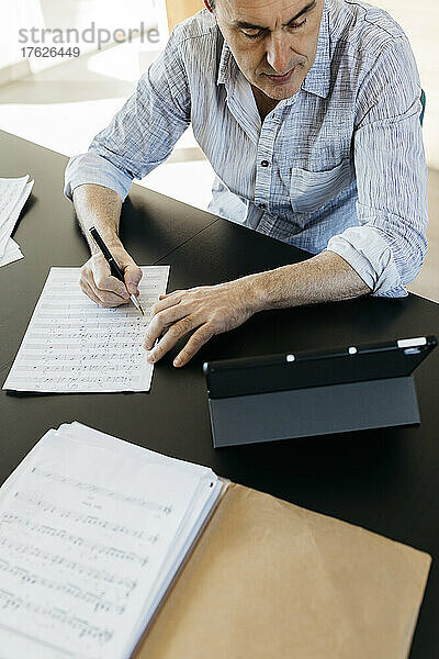 Mann schreibt zu Hause Musiknoten für E-Learning über einen Tablet-PC