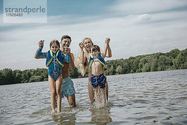 Fröhliche Eltern mit Kindern stehen am Wochenende im See