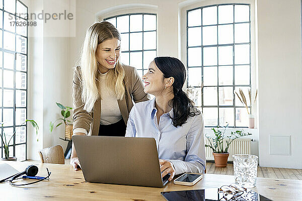 Glückliche Geschäftsfrauen mit Laptop  die im Heimbüro arbeiten