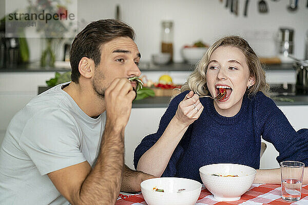 Junge Frau und Mann essen Essen und sitzen am Tisch