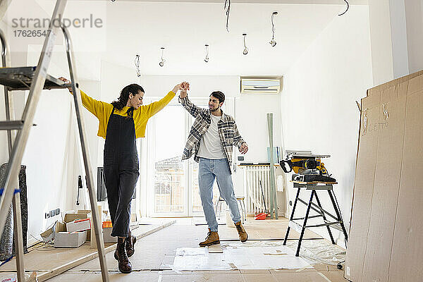 Glückliches Paar tanzt zu Hause im Wohnzimmer