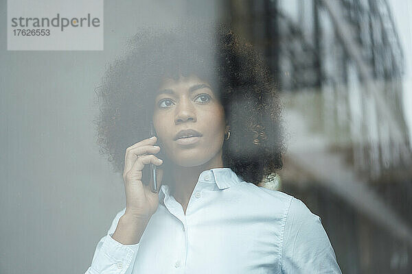 Geschäftsfrau telefoniert durch Glas