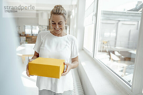 Cheerful businesswoman standing with box in office