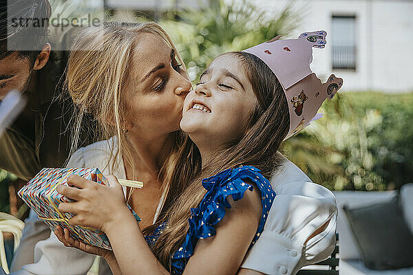 Mutter küsst Tochter mit Geschenk  um ihren Geburtstag zu feiern