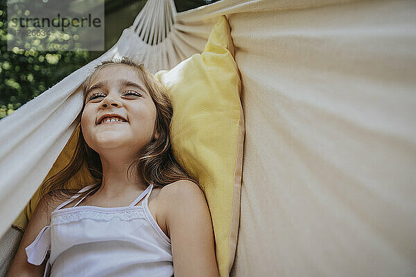 Happy girl lying in hammock at back yard