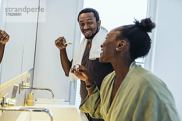 Happy couple brushing teeth in bathroom