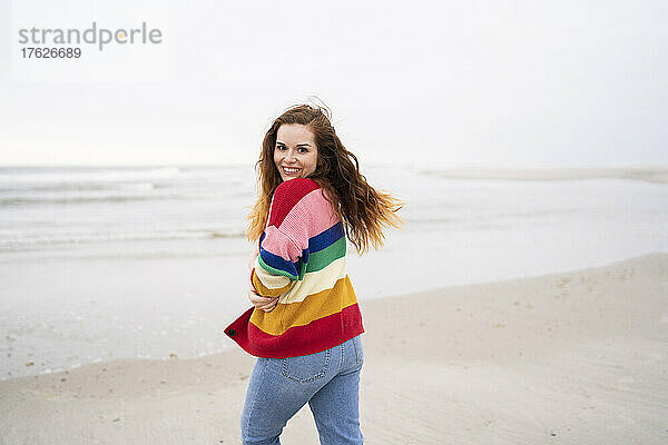 Lächelnde schöne junge Frau  die am Strand genießt
