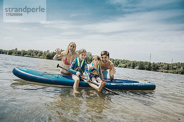 Fröhliche Familie mit Paddleboard im See am Wochenende