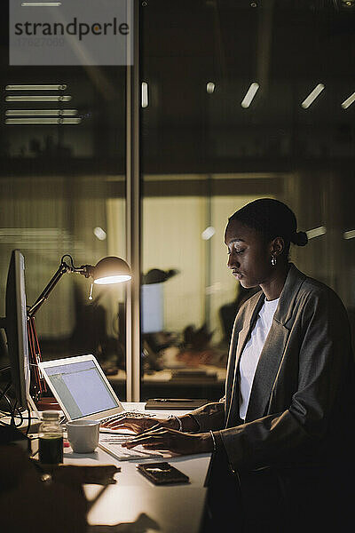 Ehrgeizige berufstätige Frau mit Laptop am Schreibtisch im Büro