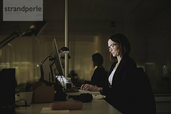 Geschäftsfrau konzentriert sich bei der Arbeit am Laptop im Büro bei Nacht