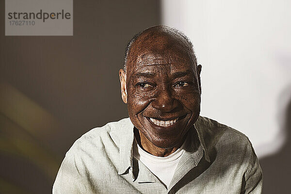 Lächelnder älterer Mann  der vor weißem Hintergrund wegschaut