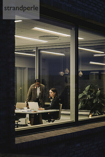 Reife Geschäftsfrau diskutiert mit einer Kollegin im Büro bei Nacht