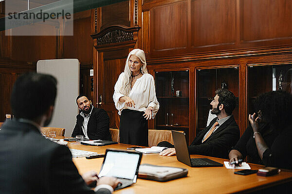 Selbstbewusste Geschäftsfrau diskutiert mit Anwälten im Sitzungssaal während einer Konferenzsitzung