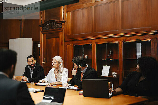Männliche und weibliche Finanzberater diskutieren in einer Konferenzsitzung im Sitzungssaal einer Anwaltskanzlei