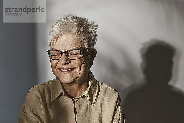 Glückliche ältere Frau mit Brille auf weißem Hintergrund