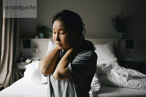 Depressive Frau sitzt mit geschlossenen Augen auf dem Bett zu Hause