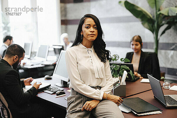 Porträt einer selbstbewussten Geschäftsfrau  die in einer Anwaltskanzlei am Schreibtisch sitzt