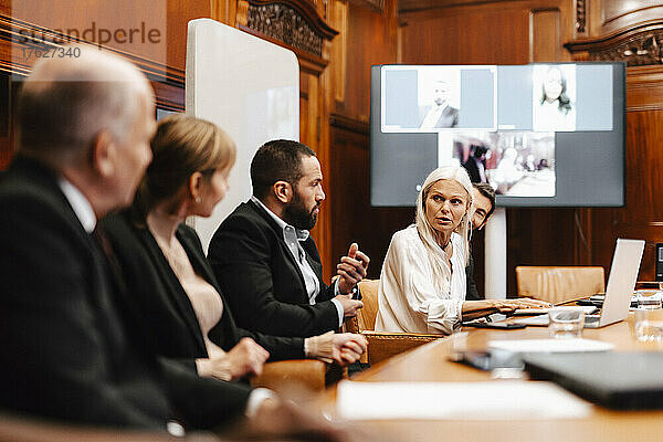 Weiblicher Finanzexperte diskutiert mit Kollegen in einer Sitzung im Sitzungssaal