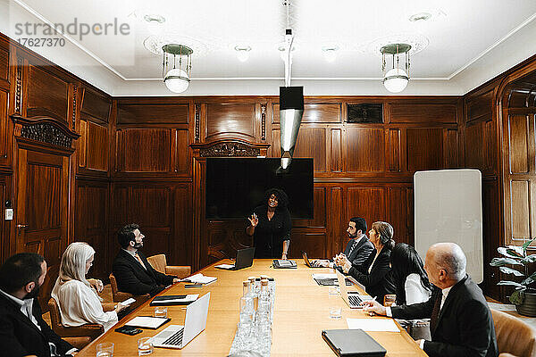 Geschäftsfrau mit multirassischen Kollegen  die während einer Konferenzsitzung im Sitzungssaal diskutieren