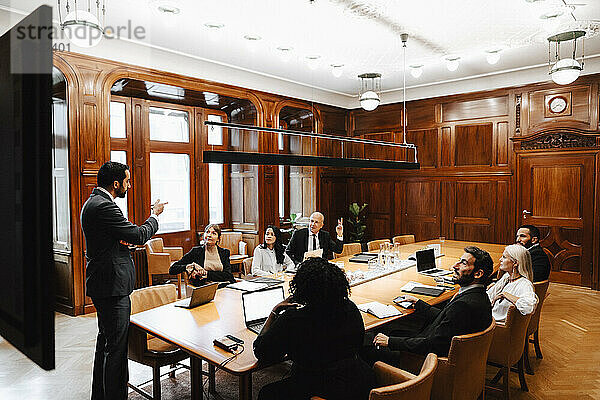 Ein Team von Anwälten bespricht sich mit einem Geschäftsmann im Sitzungssaal während einer Konferenz