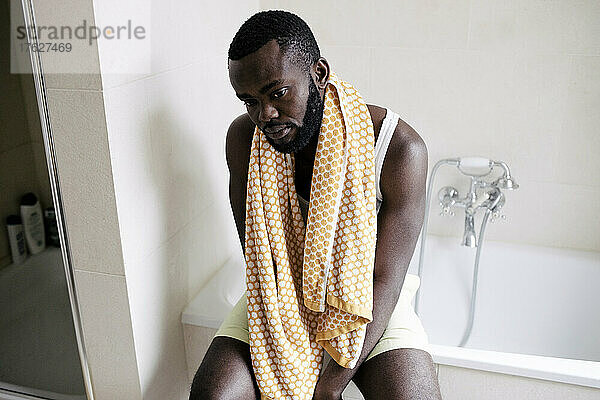 Hohe Winkel Ansicht der emotional erschöpft Mann mit Handtuch sitzt auf Badewanne zu Hause