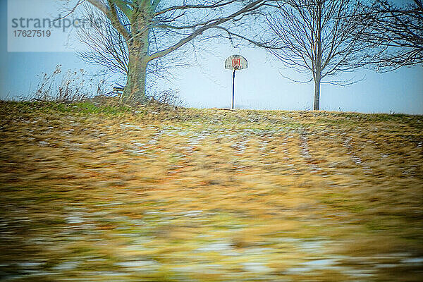 Herbstblätter wehen über einen Sportplatz.