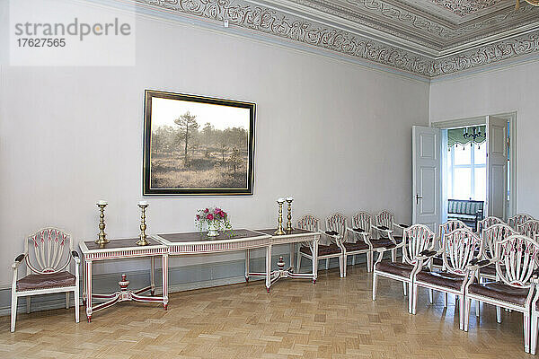 Ein großer Raum mit Parkettboden  eleganten Stühlen und Tischen.