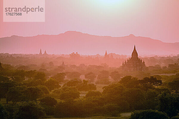 Morgendämmerung und Nebel in der Luft über dem Tempel in der Ebene in Mandalay.