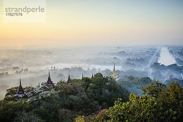 Erhöhter Blick auf die Ebene der Tempel in Mandalay  Stupas und Türme  die aus dem Nebel auftauchen  sowie historische buddhistische Stätten.
