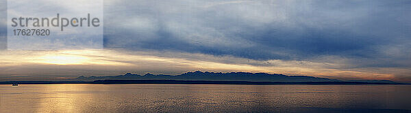 Weitwinkelaufnahme des Puget Sound mit der Olympic-Bergkette dahinter und bewölktem Himmel.