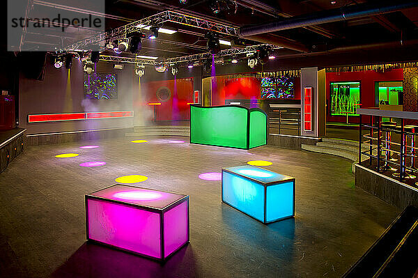 Nachtclub-Interieur  farbenfrohe Beleuchtung  Wandbildschirme und Leuchtkästen auf einer Tanzfläche.