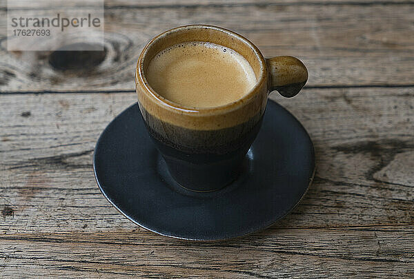Kaffee in Espressotasse und Untertasse auf Holztisch