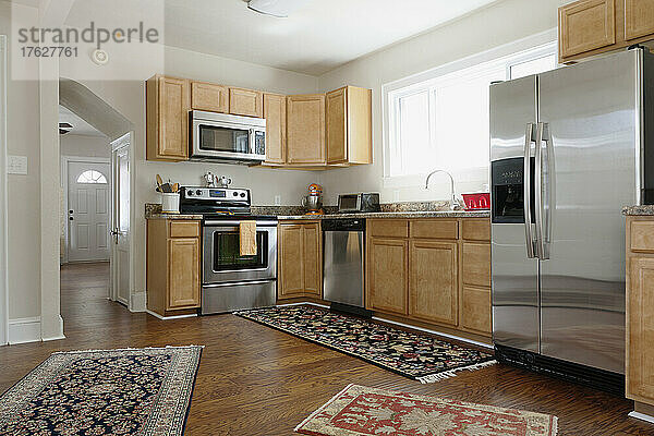 Einbauküche in einem modernen Haus  Backöfen und integrierte Geräte  Kühlschrank und Teppiche auf Holzboden