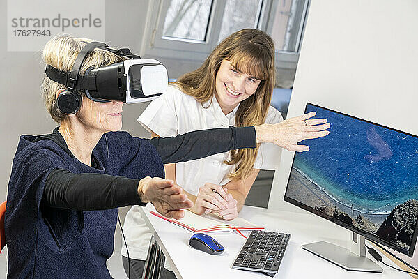 Ältere Frau während einer Therapiesitzung mit einem Virtual-Reality-Headset unter Aufsicht eines Therapeuten.