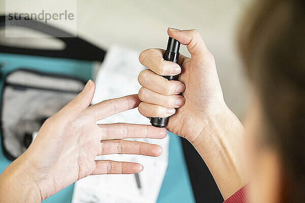 Detail der Hände einer Diabetikerin  die sich in den Finger sticht  um ihren Blutzuckerspiegel zu messen.