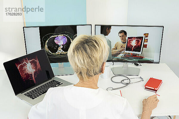 Telekonsultation zwischen zwei Ärzten mit medizinischen Bildern von Herzen auf Bildschirmen.