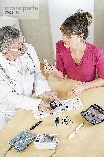 Diabetologe bringt einer Diabetikerin bei  die Hilfsmittel zur Behandlung ihres Diabetes einzusetzen.