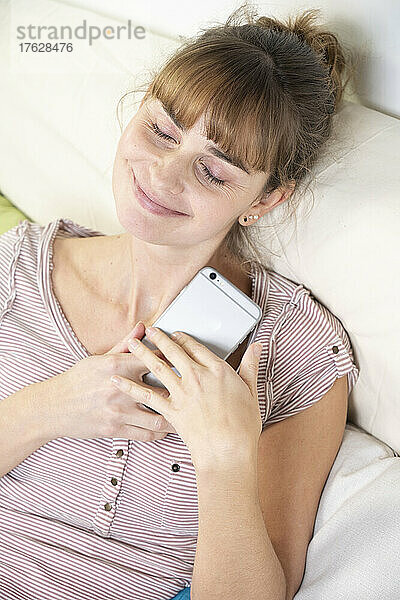 Frau verehrt ihr Smartphone. Abhängigkeit und Suchtverhalten.