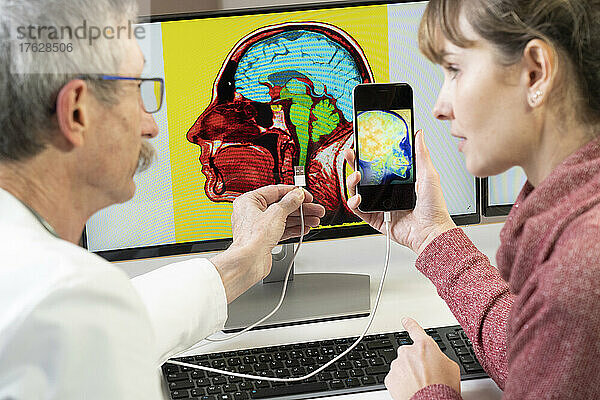 Forscher erklärt einer Frau  wie man bald sein Handy direkt im Gehirn anpinnen kann.